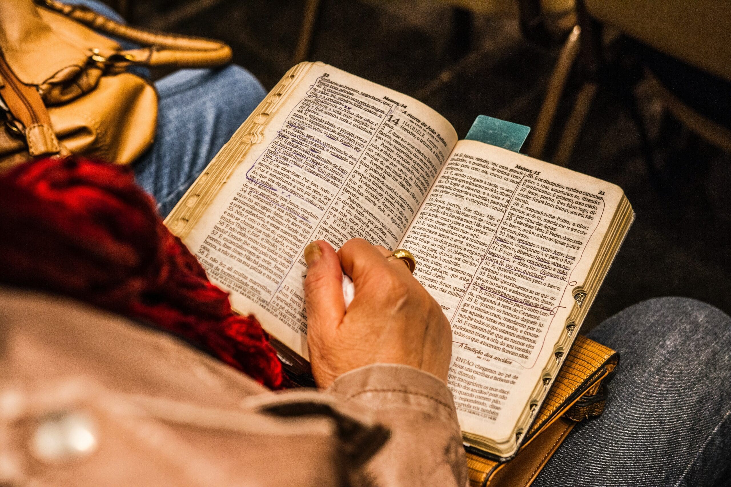 Elderly person reading old marked-up religious book
